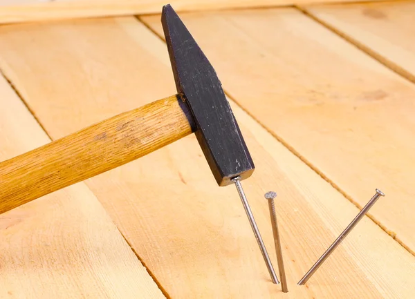 Metalen nagels in houten plank en hammer — Stockfoto