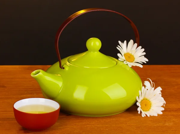 Teiera e tazza con camomilla tè su tavolo di legno su sfondo marrone — Foto Stock