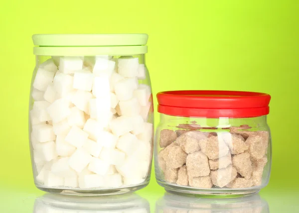 Sklenice s hnědý třtinový cukr kusové a bílé kusový cukr na barevné pozadí — Stock fotografie