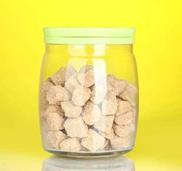 JAR s hnědý třtinový cukr paušální na barevné pozadí — Stock fotografie