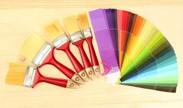 Ecsetek és világos paletta színek, fából készült háttér — Stock Fotó
