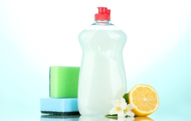 Dishwashing liquid with sponges and lemon with flowers on blue background clipart