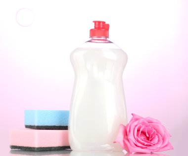 Dishwashing liquid with sponges and flower on pink background clipart