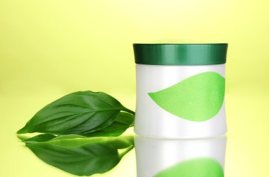 Jar of cream with green leaves on green background clipart