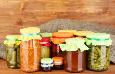 Jars with canned vegetables and fruit on wooden background close-up clipart