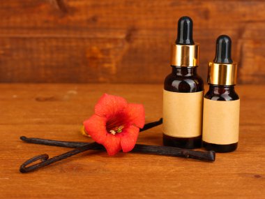 Vanilla pods with essential oil on wooden background close-up