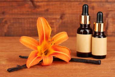 Vanilla pods with essential oil on wooden background close-up