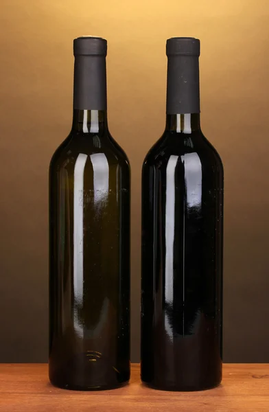 Lahví značkového vína na dřevěný stůl na hnědé pozadí — Stock fotografie