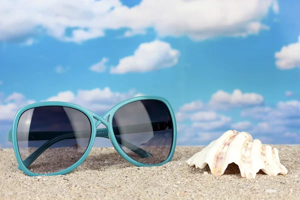Elegáns női napszemüveg, a shell, a strandon — Stock Fotó