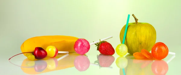 stock image A lot of tasty lollipops with fruit on green background