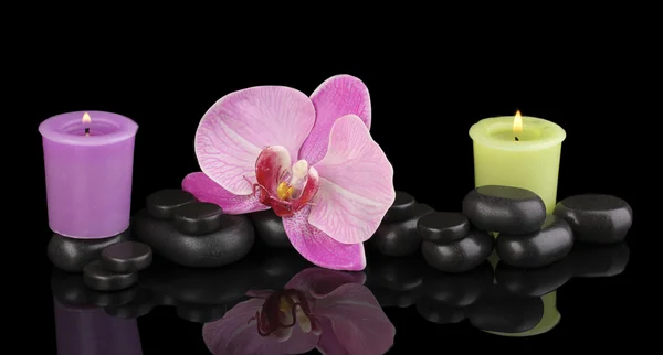 Wellness kameny s orchidej květina a svíčky, které jsou izolovány na černém pozadí — Stock fotografie