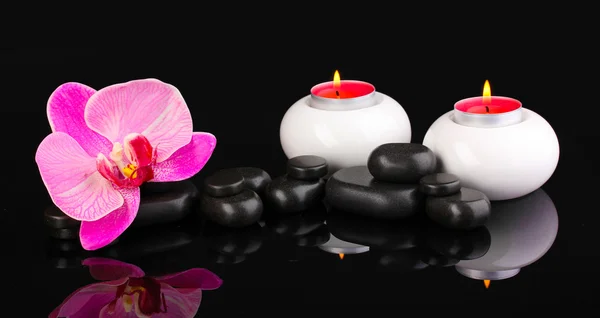 Spa stenen met orchideebloem en kaarsen geïsoleerd op zwart — Stockfoto