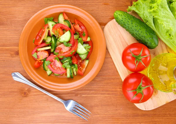 Fräsch sallad med tomater och gurkor på trä bakgrund — Stockfoto
