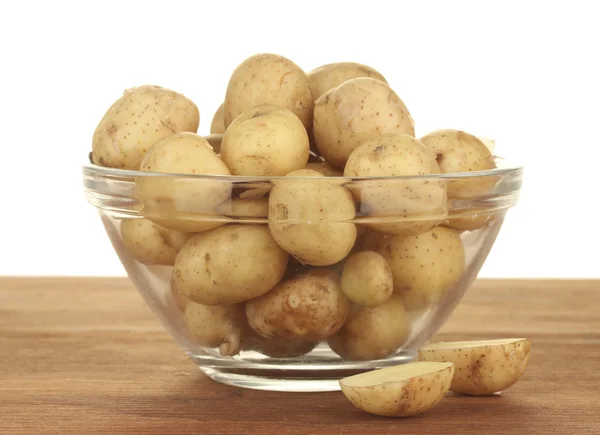 Young potatoes in a glass bowl on a table on white background — Stock Photo, Image
