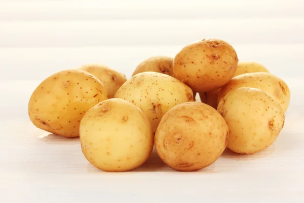 Mladí brambory na bílý dřevěný stůl detail — Stock fotografie