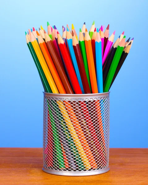 Cam ahşap masa mavi arka plan üzerinde renkli kalemler — Stok fotoğraf