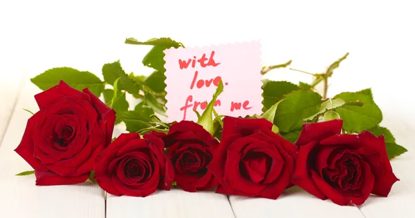 Bouquet of red roses with note on a white wooden table close-up — Stock Photo, Image