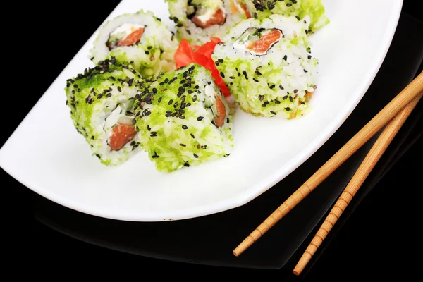 Tasty rolls served on white plate with chopsticks isolated on black — Stock Photo, Image