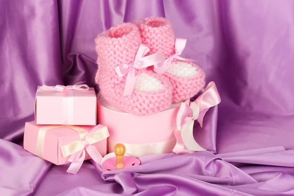 Różowe buty dla dzieci, smoczek, prezenty na tle jedwab — Zdjęcie stockowe