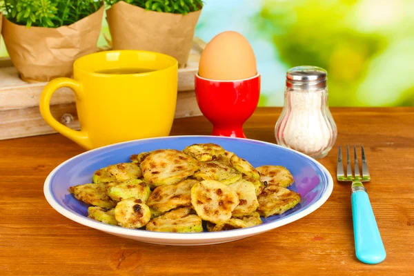 Zucchine fritte con uova e caffè a colazione su tavolo di legno su sfondo verde — Foto Stock