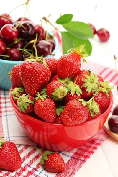 Fresas maduras y bayas de cereza en cuencos sobre mesa de madera blanca — Foto de Stock