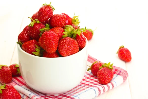 Fresas maduras dulces en tazón sobre mesa de madera blanca — Foto de Stock