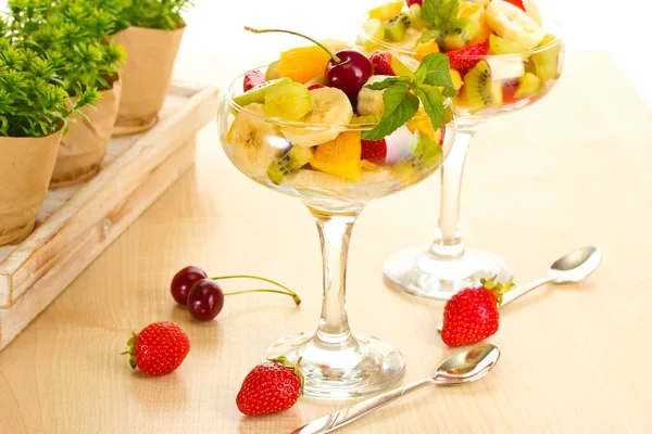 Vers fruit salade en aardbeien op houten tafel — Stockfoto