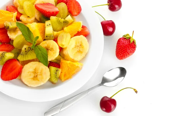 Vers fruit salade op plaat en bessen geïsoleerd op wit — Stockfoto