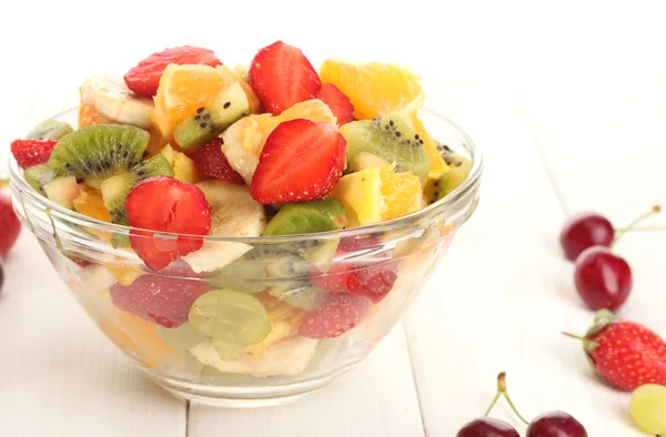 Glasschale mit frischem Obstsalat und Beeren auf weißem Holztisch — Stockfoto