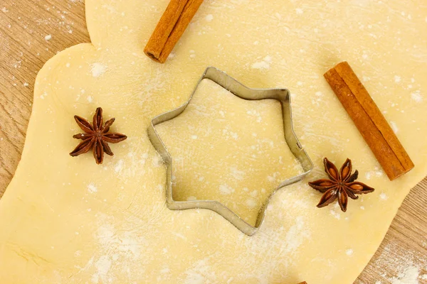Latas de biscoitos na massa de farinha estendida com ervas em um close-up de mesa de madeira — Fotografia de Stock
