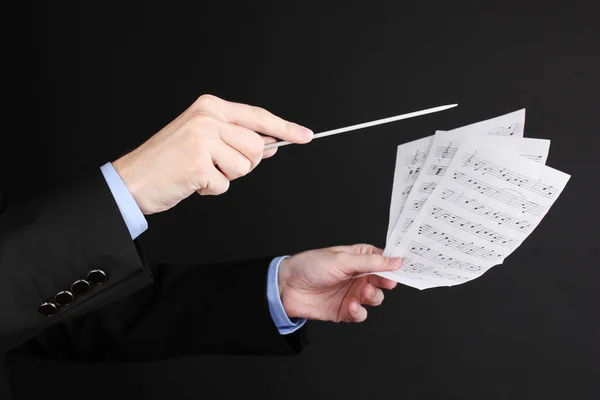 Manos de director de música con bastón y notas aisladas en negro — Foto de Stock