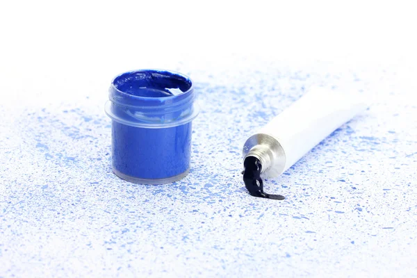Tarro con gouache azul y tubo con acuarela azul sobre fondo de spray azul close-up —  Fotos de Stock