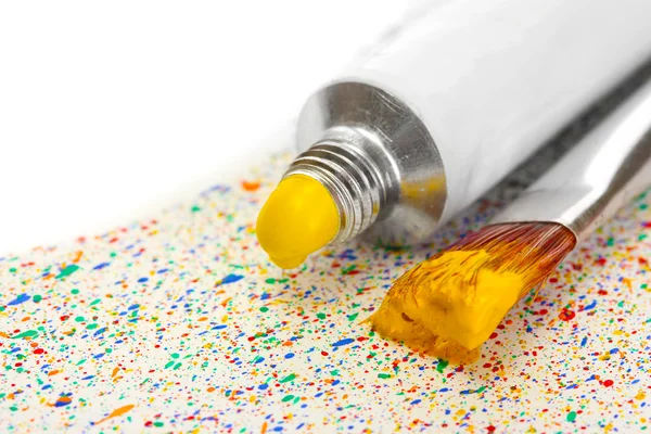 Brushes with colorful paint and tube with watercolor on colorful splashes background close-up — Stock Photo, Image
