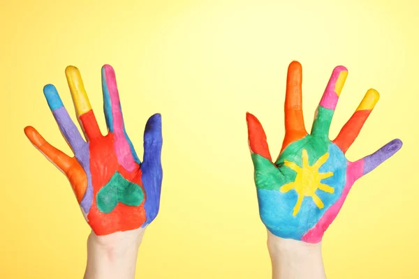 Brightly colored hands on yellow background close-up — Stock Photo, Image