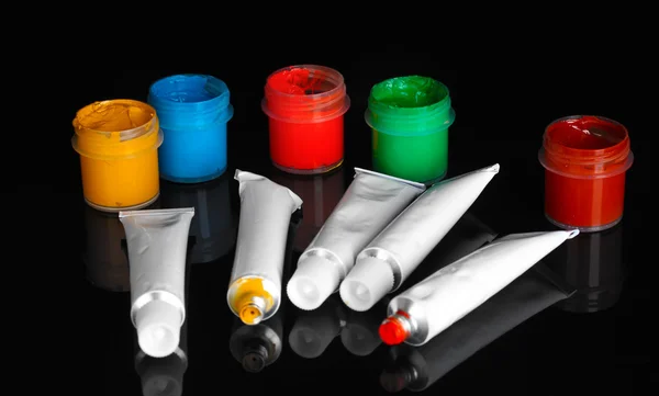 Tubos com aquarelas coloridas e frascos com guache isolado em fundo preto close-up — Fotografia de Stock