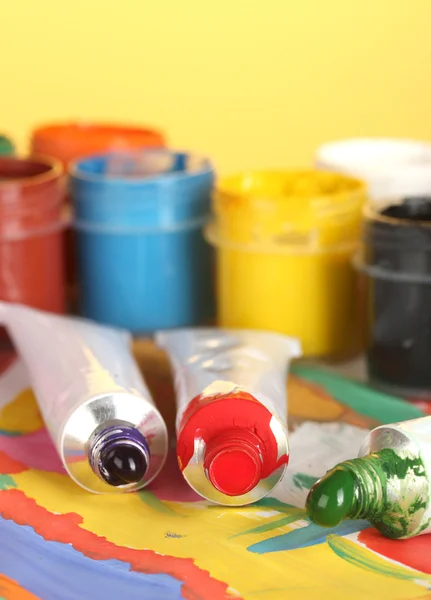 Tubes with colorful watercolor and jars with gouache on colorful picture close-up — Stock Photo, Image