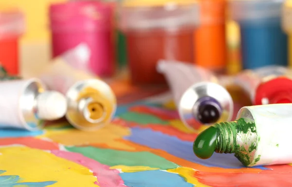 Трубки с красочной акварелью и баночки с гуашью на красочной картине крупным планом — стоковое фото