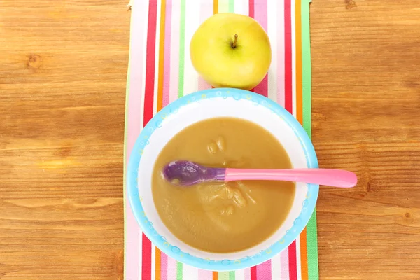 Alimenti per bambini Apple in un piatto su tovagliolo colorato su tavolo di legno primo piano — Foto Stock