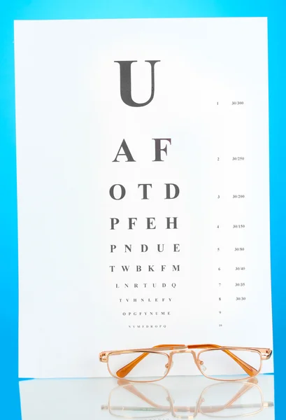 Gráfico de teste de visão com óculos no fundo azul close-up — Fotografia de Stock