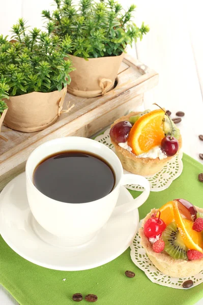 Filiżankę kawy i słodkie ciasta z owocami na drewnianym stole — Zdjęcie stockowe