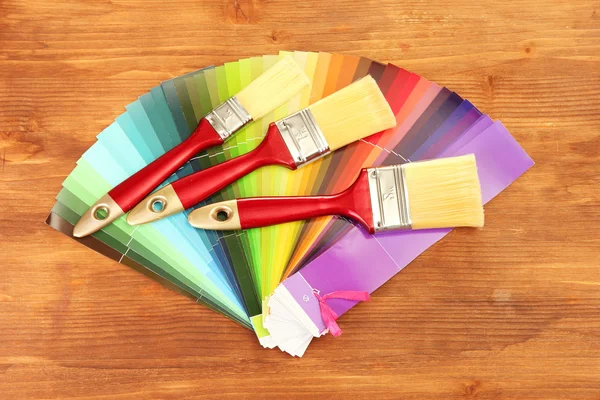 Pinceaux et palette de couleurs vives sur fond en bois — Photo