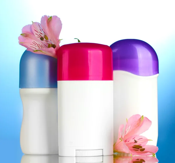Desodorizantes com flores no fundo azul — Fotografia de Stock