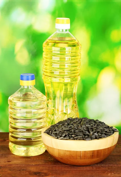 Solrosolja i flaskor med solrosfrön på grön bakgrund närbild — Stockfoto