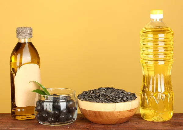 Olivlundar och solrosfält olja i flaskorna på gul bakgrund närbild — Stockfoto