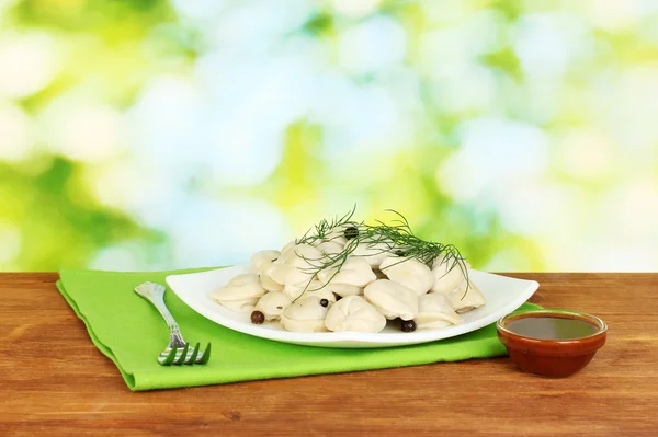 Вкусные приготовленные пельмени в блюде на ярко-зеленом фоне — стоковое фото