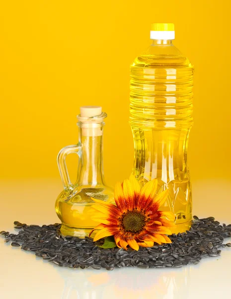 Sonnenblumenöl in einer Plastikflasche und kleiner Karaffe auf gelbem Hintergrund — Stockfoto