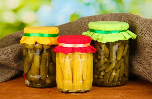 Burkar med konserverade grönsaker på grön bakgrund närbild — Stockfoto
