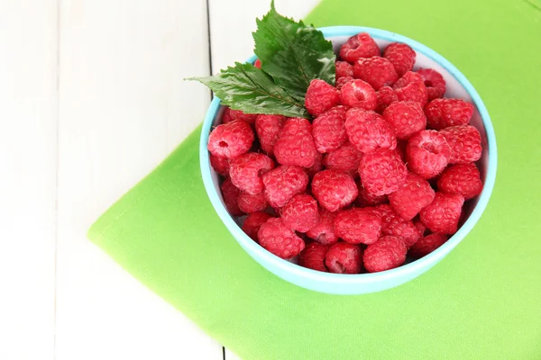 Fresh raspberries in bowl on white wooden background close-up — Stock Photo, Image