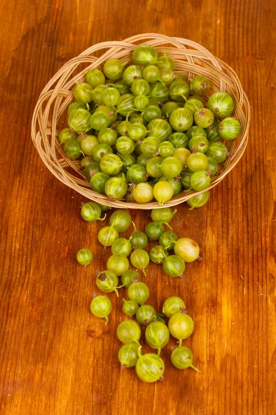 Gröna krusbär i korg på trä bakgrund — Stockfoto