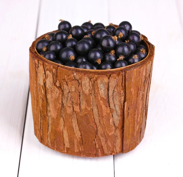Cassis dans une tasse en bois sur fond en bois — Photo